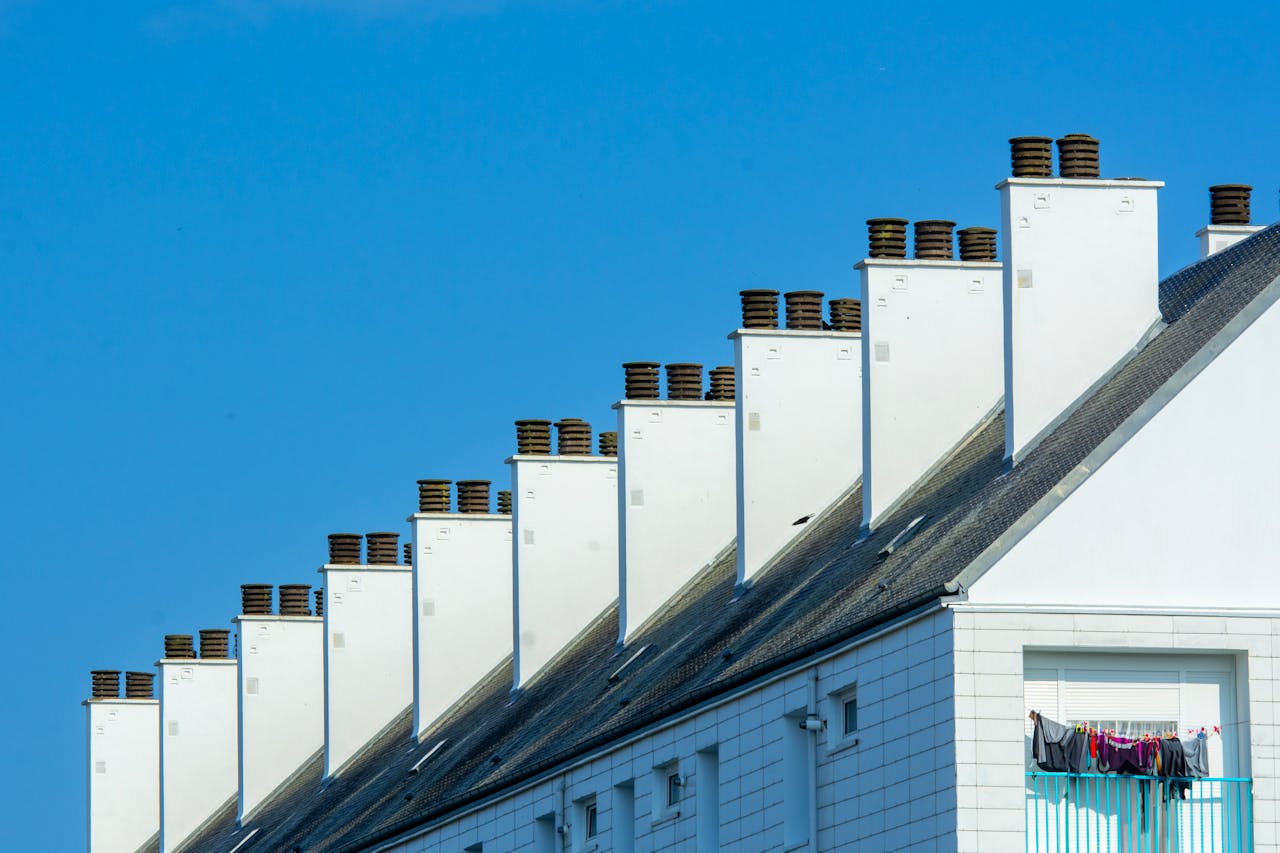 Home Row of chimneys on modern residential buildings under a clear blue sky. Urban architecture with rooftops.